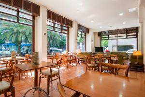 un restaurante con mesas y sillas de madera y ventanas en Hotel Alcántara, en Cáceres