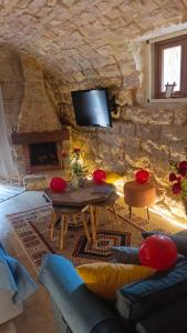 a living room with a stone wall with a tv at Aal Aoudeh guesthouse in Dayr al Qamar
