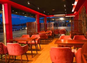 a restaurant with red chairs and tables and windows at Ramadia Ran Mal Holiday Resort in Moratuwa