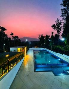 a swimming pool with a sunset in the background at West wind Resort in Meppādi