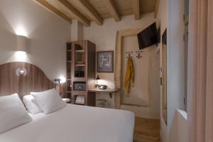 a bedroom with a white bed and a television at Académie Hôtel Lyon in Lyon