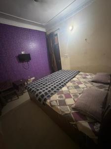 a bedroom with a bed and a purple wall at Hotel JMR in Sohāna