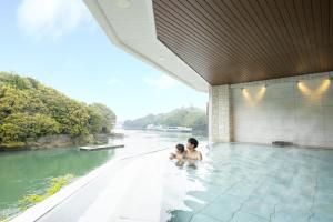 two people in a swimming pool next to a river at Ooedo Onsen Monogatari Premium Toba Saichoraku in Toba