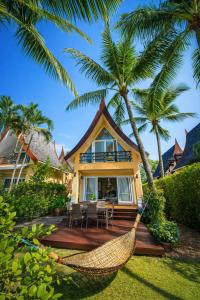 a hammock in front of a house with palm trees at Tankini Beachfront Villa in Ban Khlong Son