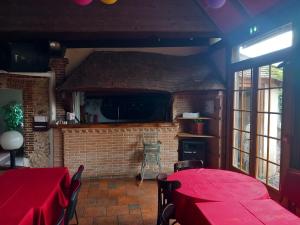 a dining room with red tables and a brick wall at Le Motel Saint Martin in Verneuil d'Avre et d'Iton