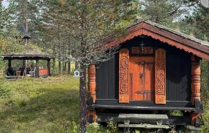 a small house in a field with a tree at Gorgeous Home In Flatdal With Sauna in Flatdal