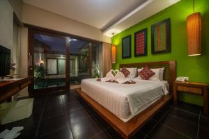 a bedroom with a bed with a green wall at Gaing Mas Jimbaran Villas by Gaing Mas Group in Jimbaran +97 photos