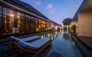 a swimming pool with lounge chairs next to a building at Gaing Mas Jimbaran Villas by Gaing Mas Group in Jimbaran