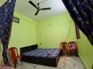 a bedroom with a bed and two red chairs at Comfort Studio Type Appartment - Kolkata in Nager Bazaar