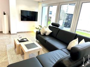 ein Wohnzimmer mit einer schwarzen Ledercouch und einem Tisch in der Unterkunft Ferienwohnung Forstblick in Kranenburg