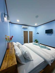 a bedroom with a large white bed with a wooden table at Khaosok Bluesky Hotel in Khao Sok National Park