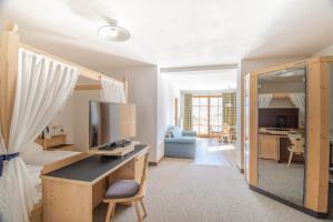 a bedroom with a desk with a computer and a room at Hotel Vermoi in Laces