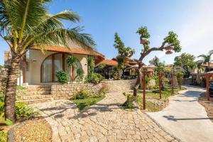 a house with palm trees and a brick walkway at Homestay coffee Hoàng Nhạn in Mỹ Hòa (1)