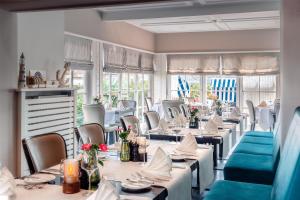 a dining room with tables and chairs and windows at Dorint Strandresort & Spa Westerland/Sylt in Westerland