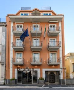 an orange building with balconies and flags on it at Hotel Bruman in Caserta