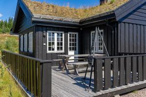 a black cabin with a picnic table on a deck at Solsiden 16B by Vacation Trysil in Trysil