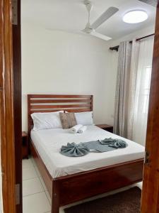 a bedroom with a bed with white sheets and a ceiling at Leona Homes in Mombasa +6 photos