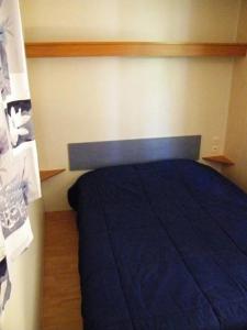 a bedroom with a bed with a blue blanket at Camping 3 étoiles - Piscine - ccbfeb0 in Mayrac