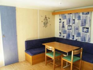 a room with a blue couch and a table and chairs at Camping 3 étoiles - Piscine - ccbfeb0 in Mayrac