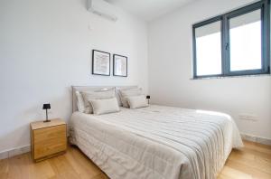 a white bedroom with a large bed and two windows at Prestige 402 1 BED in Paphos +17 photos