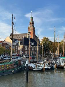 a group of boats docked in a harbor with a building at Ferienwohnungen Grueßing, 15014 in Leer
