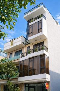 a tall white building with balconies on it at Mèn Mén Home in Phú Thọ