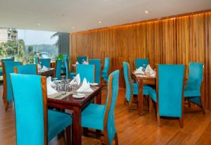 a dining room with blue chairs and wooden tables at Serene Kandy in Kandy