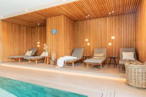 una piscina con tre sedie e una piscina di Hotel Strandhus a Cuxhaven