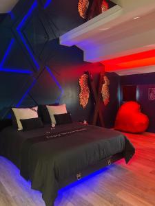 a bedroom with a bed with red and blue lights at Suite craz'in Love Room, jacuzzi, cinéma, climatisation, parking in Beaucaire