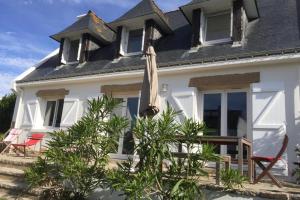 a white house with an umbrella in front of it at Grande maison proche plage et centre ville avec grand parking in Quiberon