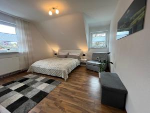 a bedroom with a bed and a couch and two windows at Ferienwohnung Balkon Grupe in Stadtoldendorf