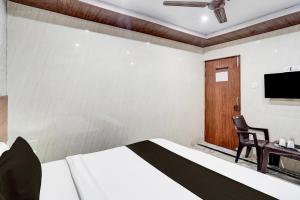 a bedroom with a bed and a desk and a tv at Hotel O Govind Nagar Kanpur Formerly Maharoopa Palace in Kānpur +40 photos