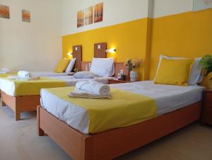 two beds in a room with yellow walls at on the STRIP studio 3 in Kavos