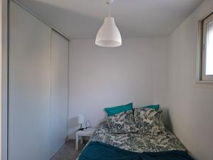 a bedroom with a bed and a white wall at Chez Anne in La Ciotat