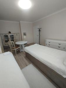 a white bedroom with two beds and a table at Sweet home in Tauragė