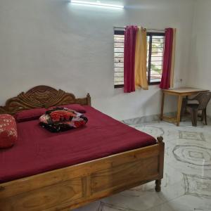 a bedroom with a wooden bed with a red blanket at shreejikunj in Bolpur