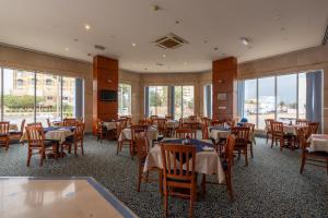 a dining room with tables and chairs and windows at Lavender Hotel Sharjah in Sharjah