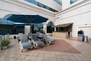 a group of chairs and an umbrella in front of a building at Lavender Hotel Sharjah in Sharjah