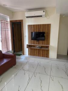 a living room with a couch and a tv on a wall at hotel belva in Ahmedabad