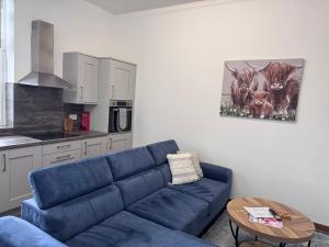 a living room with a blue couch and a table at Ben Lomond Apartment - Macaulay Letting in Alexandria