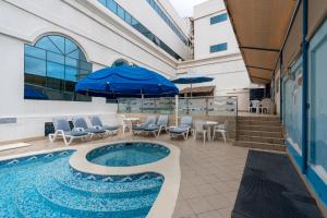 a pool with chairs and umbrellas next to a building at Lavender Hotel Sharjah in Sharjah