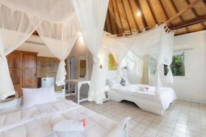 a bedroom with two white beds and a table at Taman Indrakila in Ubud