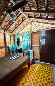 a woman standing in a room with a bed at This is it Stays - Beach View Rooms & Huts in Arambol