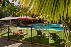 a fence with chairs and umbrellas next to a pool at Apartamentos El Palmeral de Madaria in Alicante
