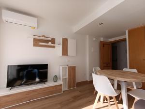 a living room with a wooden table and a television at La Ostra De Benidorm in Benidorm +55 photos