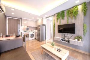 a living room with a tv and a table and a kitchen at Dazzle Residence Sukhumvit Bangkok in Bangkok