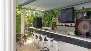 a bar with white chairs and a counter with a tv at Silver Coast Pool & Resort Villas in Arnal