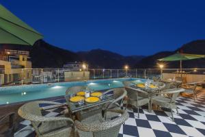 a patio with tables and chairs next to a pool at Vyom Boutique Hotel by Aramah in Rishīkesh