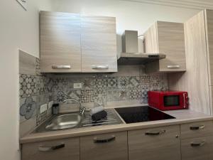 a kitchen with a sink and a red microwave at Lux Maris in Mazara del Vallo