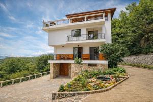 a large white house with a balcony and a garden at Villa High Point in Pravets